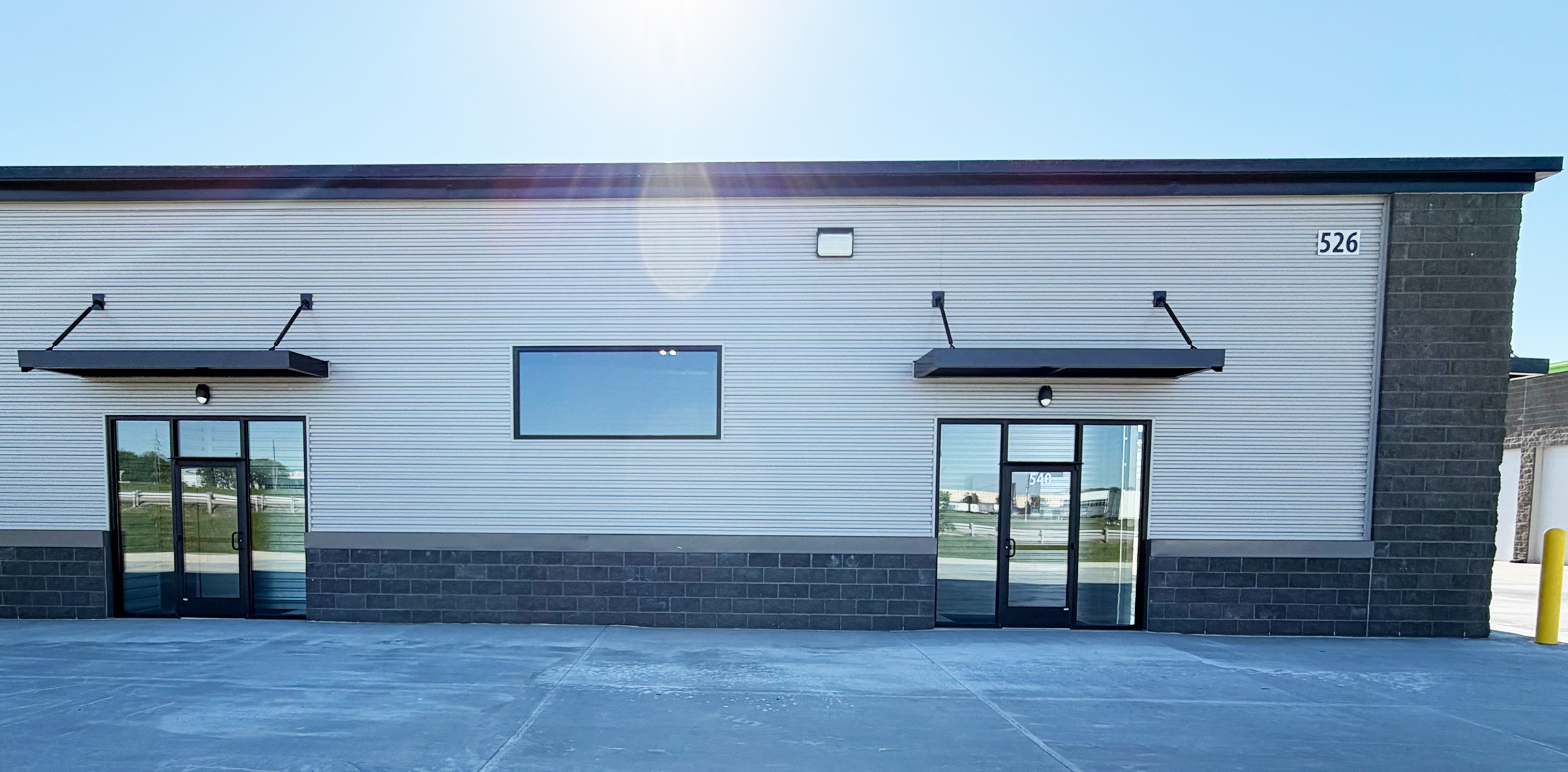 Modern commercial building frontage with two entrances, large windows, black awnings, and street numbers 526 and 540 visible.