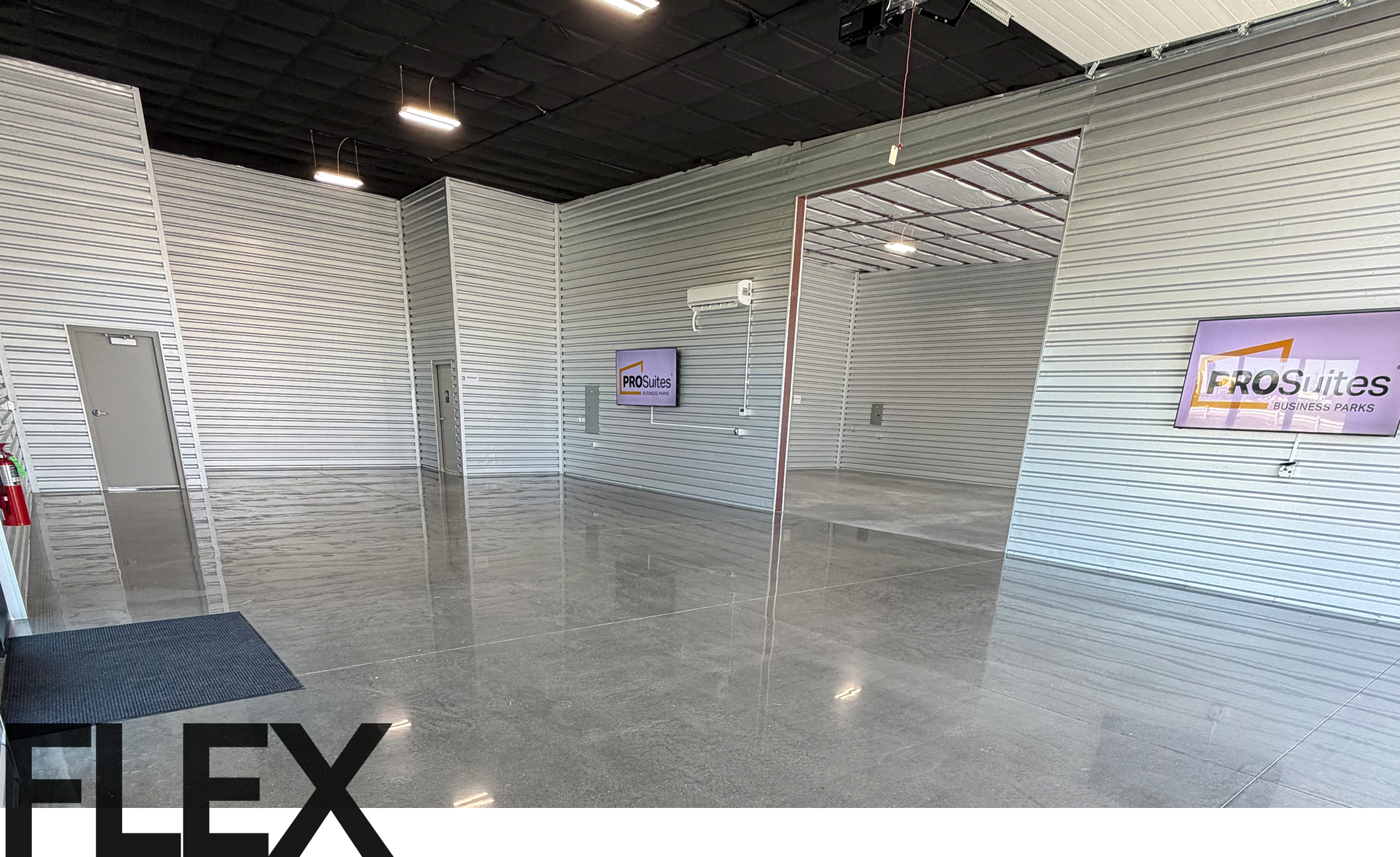 Interior of a modern office showroom with gray corrugated metal walls, high black ceiling, and a glossy gray floor; PRO Suites Business Parks sign on the wall.